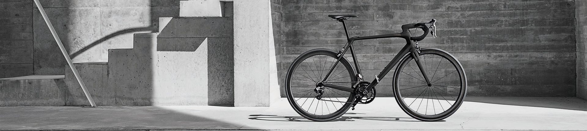 Vélo de route carbone photographié devant un mur en béton